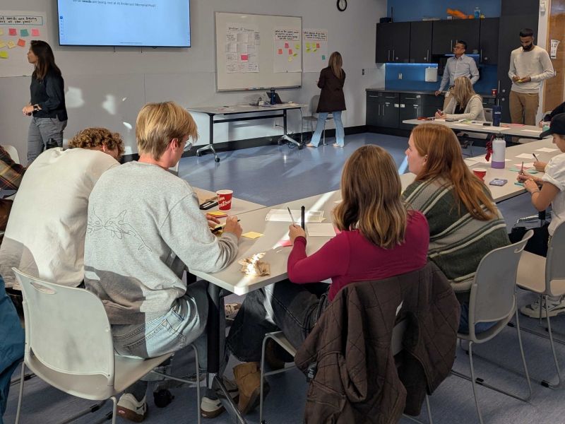 Group of people sitting at a table writing down thoughts.
