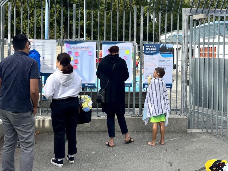 Three people at Al Anderson Memorial Pool looking at engagement boards.